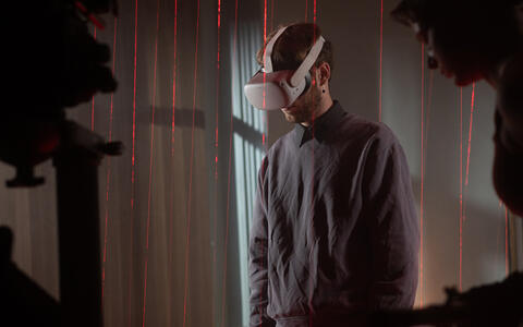 IMpression aus dem Kamera-Workshop Licht und Farbe. Zu sehen ist ein Teilnehmer mit VR-Brille in einem Laser-Raster.