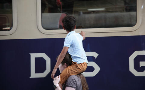 Mann mit Junge auf Schultern am Bahnsteig