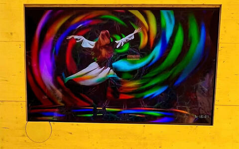 Fernseher zeigt eine animierte tanzende Frau. Sie ist von wirbelnden Farben umgeben