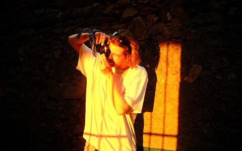Ein junger Mann macht ein Foto und wird von der Sonne angestrahlt.