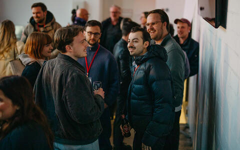 Eine Gruppe Menschen steht in einem Foyer und Leute unterhalten sich