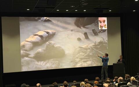 Ein Mann präsentiert im Kino auf einer Leinwand eine Animation vor Publikum