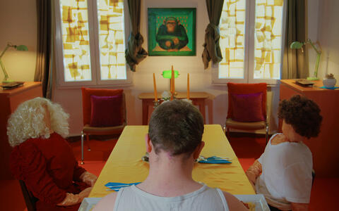 Ein Mann sitzt mit zwei Puppen an einem Tisch