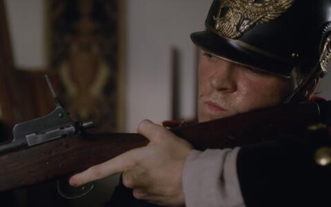 Eine Nahaufnahme des Gesichts eines Mannes mit einem Helm aus dem 19. Jahrhundert, der ein Gewehr hält.
