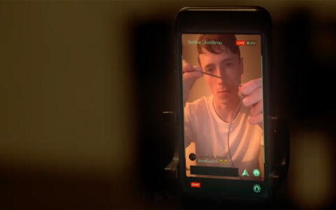 Ein Handybildschirm während eines Livestreams. Ein Mann hält eine Schnur in die Kamera