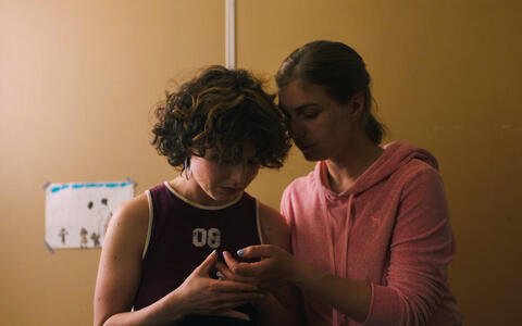 Zwei junge Frauen schauen gemeinsam auf ein Handy