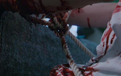 Gefesselte, blutige Arme mit Blut, das auf weißen Stoff tropft