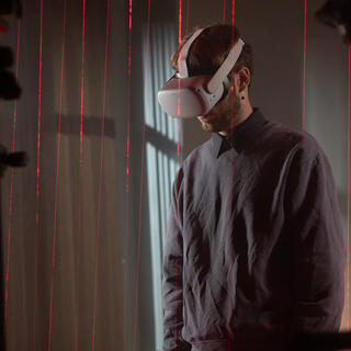 IMpression aus dem Kamera-Workshop Licht und Farbe. Zu sehen ist ein Teilnehmer mit VR-Brille in einem Laser-Raster.