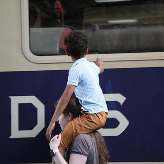 Mann mit Junge auf Schultern am Bahnsteig