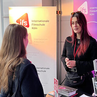 Zwei junge Frauen unterhalten sich an einem Messestand