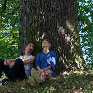 Zwei Menschen sitzen unter einem Baum