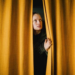 Am Set von »Exponat« eine Schauspielerin schaut hinter einem gelben Vorhang hervorifs filmschule